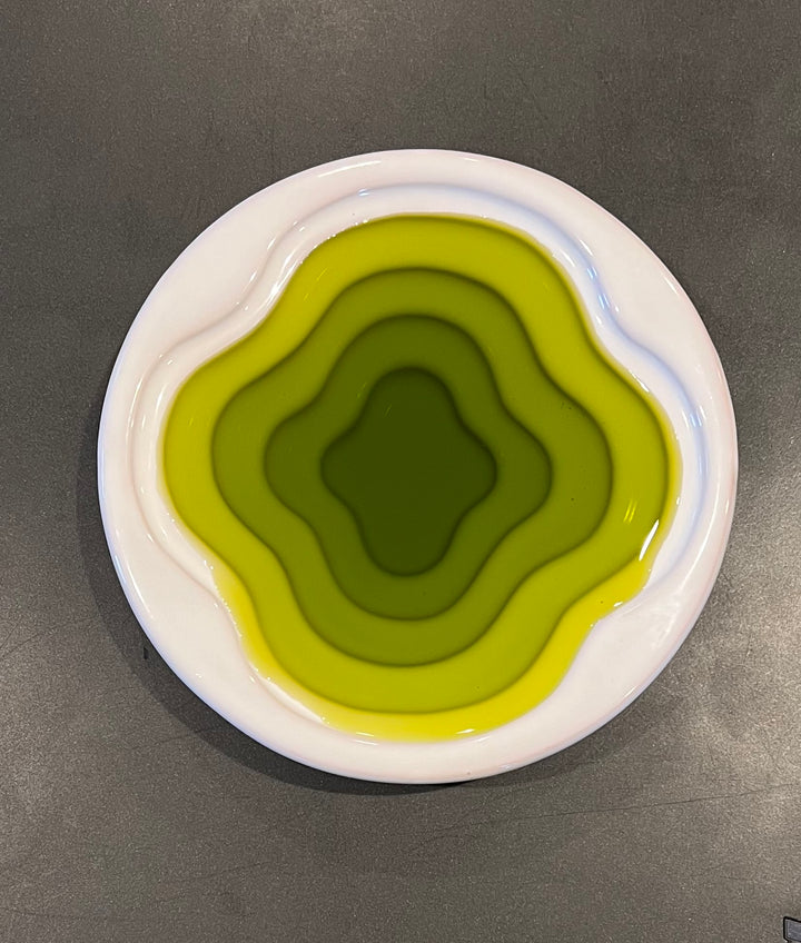olive oil poured into a white dish with layers to show the deep green of the oil.